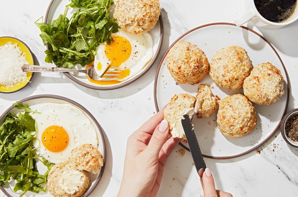 A baker buttering a Cacio e Pepe (Cheese and Pepper) Scone - select to zoom